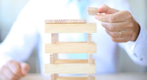 Man building a structure out of wooden blocks to represent a framework